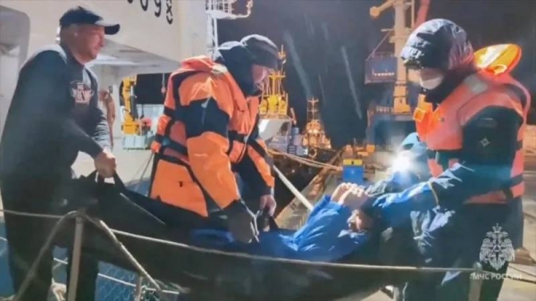 Rescuers leave a vessel while carrying a man, who was reportedly saved after his sailboat had drifted for 67 days in waters edging the north-western Pacific