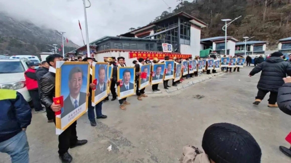 New residents, carrying portraits of Chinese leader Xi Jinping, are welcomed to Demalong village in a ceremony on December 28, 2023