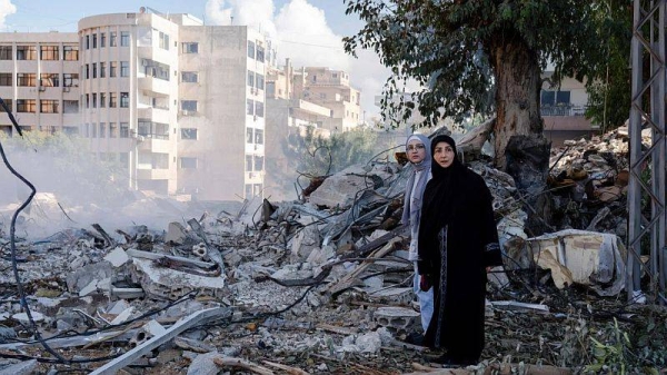 Two women stand next to destruction in the city center of Tyre, following an Israeli airstrike in the southern Lebanese port city