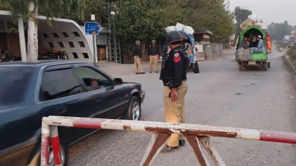 A police officer stands guard at a checkpoint along a dusty highway in the Khyber Pakhtunkhwa province