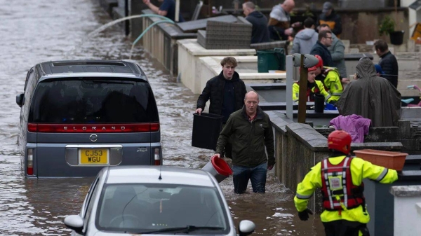 People wade through water on Sion Street in Pontypridd, Wales on November 24, 2024