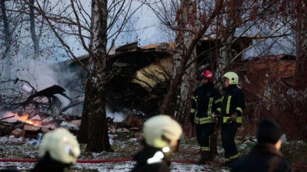 Wreckage of a crashed plane with emergency services staff at the scene