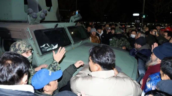 Protesters crowd around a military vehicle in front of the National Assembly building