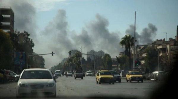 Smoke rising on the horizon of a street in Damascus