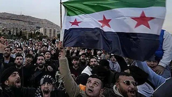 Syrian citizens wave the revolutionary flag and shout slogans, as they celebrate during the second day of the take over of the city by the insurgents in Damascus, Syria, Monday