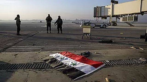 A Syrian flag lies on the ground as opposition fighters stand on the tarmac of the Aleppo international airport