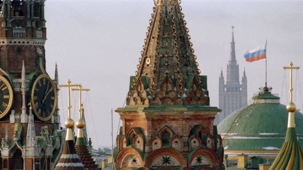 The Russian flag flies over the Kremlin between the spires of St. Basil's Cathedral in Moscow, Russia -