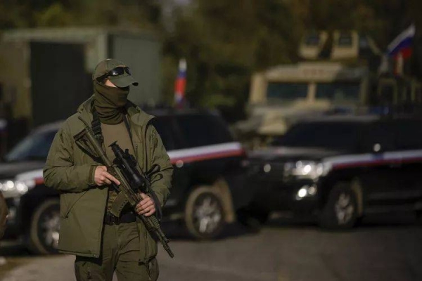 A Russian soldier stands next to a Russian military convoy as it moves along a road near the Mediterranean town of Tartus, Syria, Monday Dec. 16