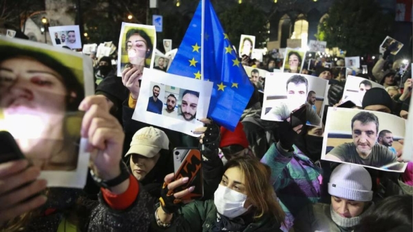 Demonstrators hold portraits of activists injured during protests during an anti-government rally outside the Parliament building in Tbilisi, Georgia, Dec. 14, 2024