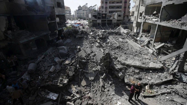 Palestinians look at the aftermath of an Israeli bombing in Nuseirat refugee camp in the Gaza Strip in June