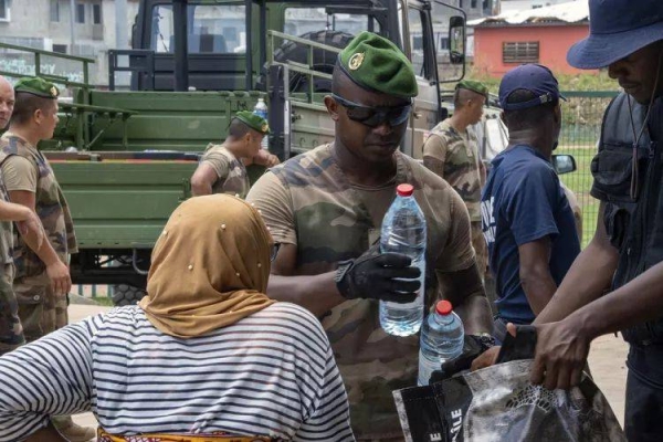 A French Army soldier giving a bottle of water to a resident in the Indian Ocean French territory of Mayotte, Wednesday Dec.18, 2024