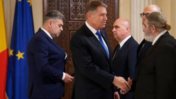 Romanian President Klaus Iohannis, right, shakes hands with government coalition leaders as Prime Minister designate Marcel Ciolacu, left, walks after being nominated to form the new government in Bucharest, Romania, Monday, Dec. 23