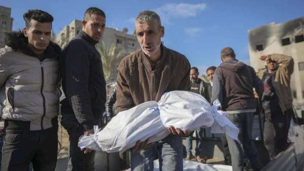 The body of an 18-month-old is carried by her uncle for burial in the aftermath of an Israeli airstrike in Khan Younis, southern Gaza Strip, on December 5