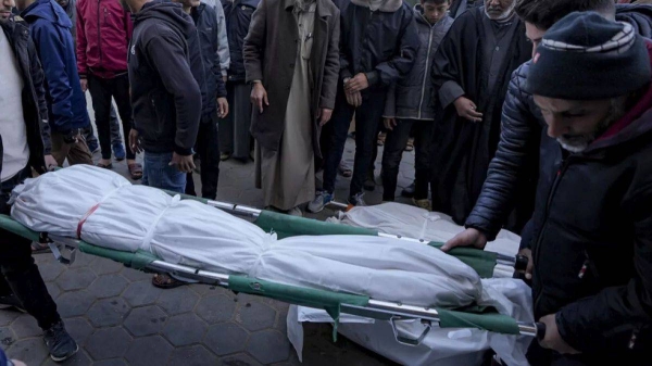 Palestinians carry the body of a relative killed in the Israeli bombardment of the Gaza Strip at Al-Aqsa Hospital in Deir Al-Balah, Tuesday, Jan. 14, 2025