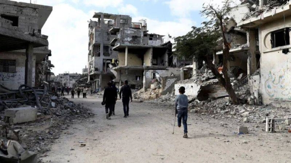 Palestinians walk past the rubble of houses and buildings in central Gaza