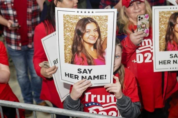 Trump rallygoers hold a sign of Riley's face saying 'say her name'