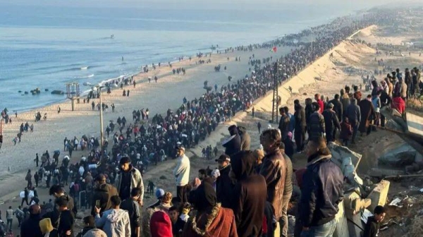 A long line of people are seen walking along the coast toward northern Gaza early Monday