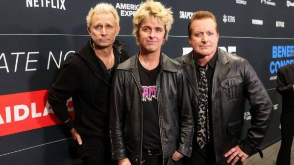 The members of Green Day pose on a carpet before the FireAid benefit concert