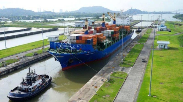 A cargo ship and tugboat sail through locks at the Panama Canal