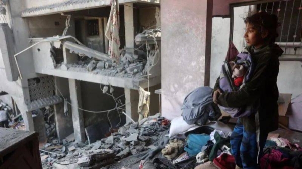 A girl searches for items at a house which was destroyed in strikes on the Shujaiya district in Gaza City on 18 March