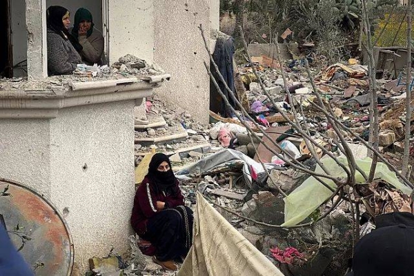 Neighbours watch as volunteers and rescue workers search for survivors among the rubble of a building hit in an air strike in Khan Younis, 20 March, 2025