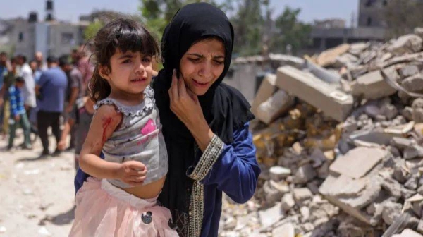 A Palestinian woman carries a girl wounded in an Israeli strike in the Saftawi neighborhood west of Jabalia in the northern Gaza Strip on May 27, 2025