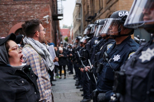 Demonstrators stand in front of police officers as they rally during a protest against federal immigration sweeps at the ICE building in San Francisco, California, on Sunday. 