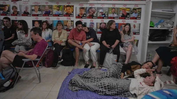 People take shelter next to photographs of Israeli hostages abducted during the Hamas attack, during air raid sirens warning of incoming strikes by Iran, 19 June 2025