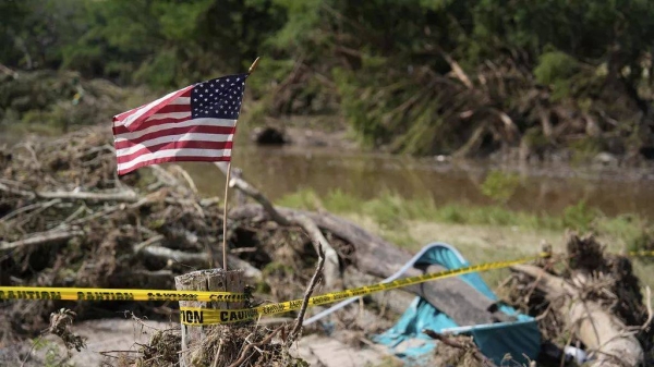 An American flag placed on a stump flies in Kerrville, Texas on Tuesday, July 8, 2025