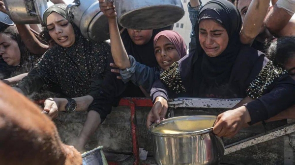 Internally displaced Palestinians, including children, hold pots as they receive food from a charity kitchen