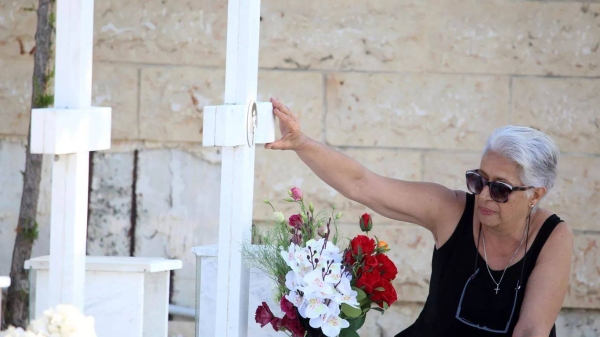 A woman touches the photo at the grave of her relative, killed in the 1974 Turkish invasion of Cyprus, in Nicosia, 20 July 2024