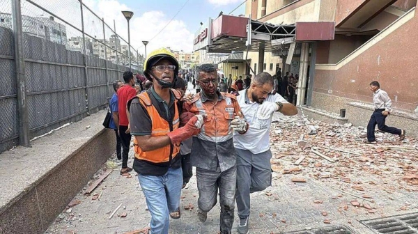 An injured emergency worker is led away by two other emergency workers