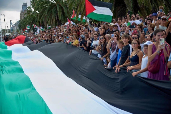 People hold Palestinian flags as they bid farewell to activists setting sail to join a civilian flotilla bound for Gaza, in Barcelona, Spain, on Sunday, August 31, 2025