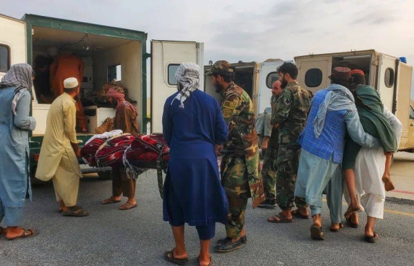 Taliban soldiers and civilians carry earthquake victims to an ambulance at an airport in Jalalabad, Afghanistan, on Monday