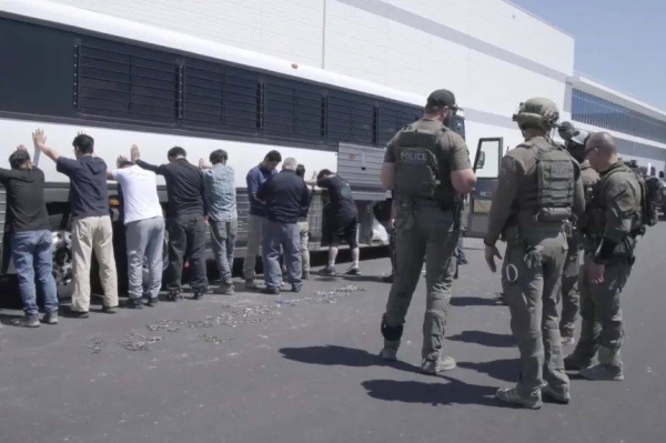 This image from video provided by US Immigration and Customs Enforcement shows manufacturing plant employees waiting to have their legs shackled at the Hyundai Motor Group’s electric vehicle plant, in Ellabell, Georgia, on Sep