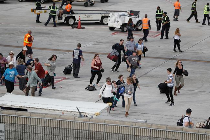 People seek cover on the tarmac of Fort Lauderdale-Hollywood International airport after a shooting took place near the baggage claim. — AFP