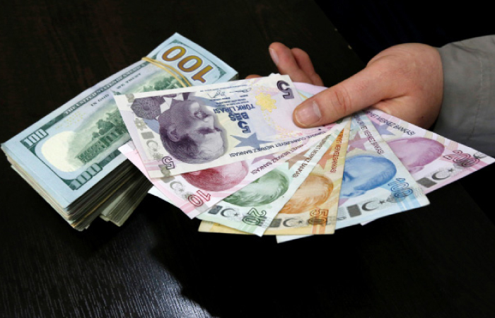 A money changer holds Turkish lira banknotes next to US dollar bills at a currency exchange office in central Istanbul. — Reuters