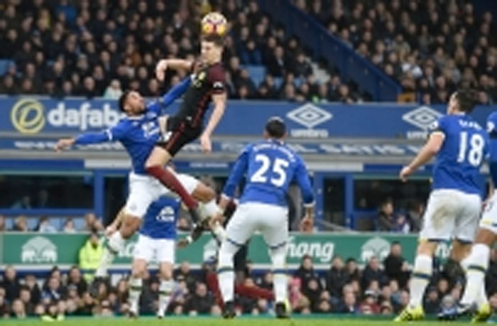Manchester City’s English defender John Stones (up) jumps for the ball against Everton’s English-born Welsh defender Ashley Williams (L) during their English Premier League match in Liverpool Sunday. - AFP
