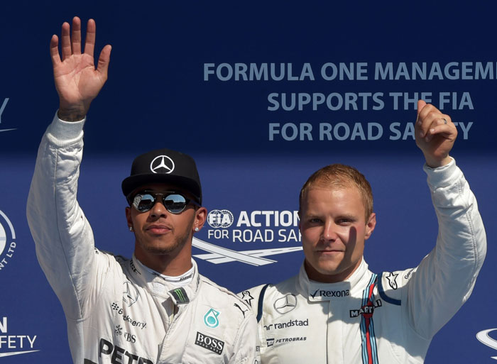 A picture taken on Aug. 22, 2015, shows pole position Mercedes AMG Petronas F1 Team's British driver Lewis Hamilton (L) and third-placed Williams Martini Racing’s Finnish driver Valtteri Bottas celebrating in the parc ferme after the qualifying session at the Spa-Francorchamps ciruit in Spa, ahead of the Belgian Formula One Grand Prix. - AFP