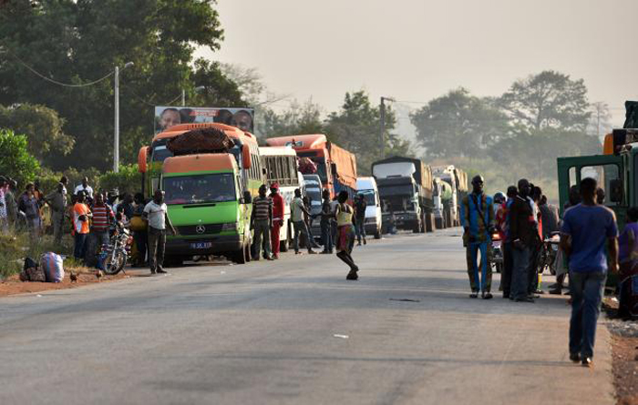 People wait near trucks and buses, some 15 km from Bouake, on Friday, after soldiers seized control of the city in a protest over pay. — AFP