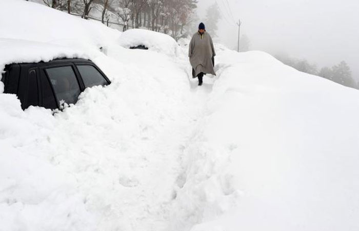 Kashmiri men walk on a snow-covered road after a heavy snowfall in Tangmarg, some 34 km north of Srinagar, India, on Sunday. — AFP