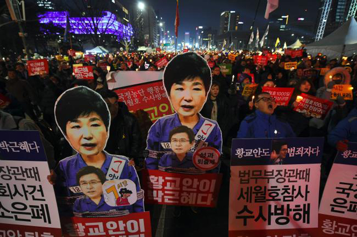 Protesters carry portraits of South Korea's President Park Geun-Hye during a protest demanding the impeached President resign immediately in Seoul on Saturday. — AFP