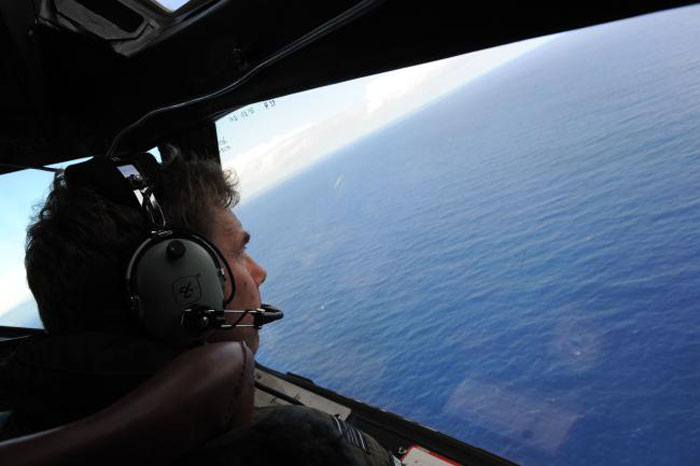 This file photo taken from a Royal New Zealand Airforce (RNZAF) P-3K2-Orion aircraft on April 13, 2014 shows co-pilot and Squadron Leader Brett McKenzie helping to look for objects during the search for missing Malaysia Airlines flight MH370, off Perth in Western Australia. — AFP