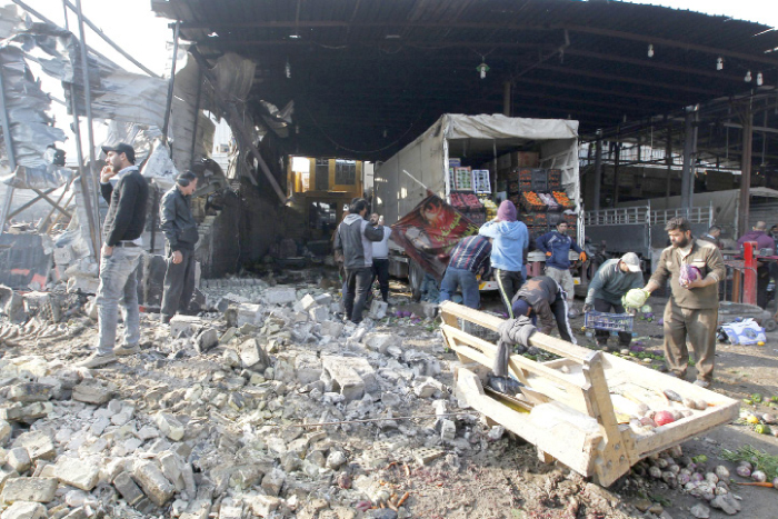 Iraqis salvage vegetables from the site of an attack at Baghdad’s main vegetable market on Sunday. — AFP