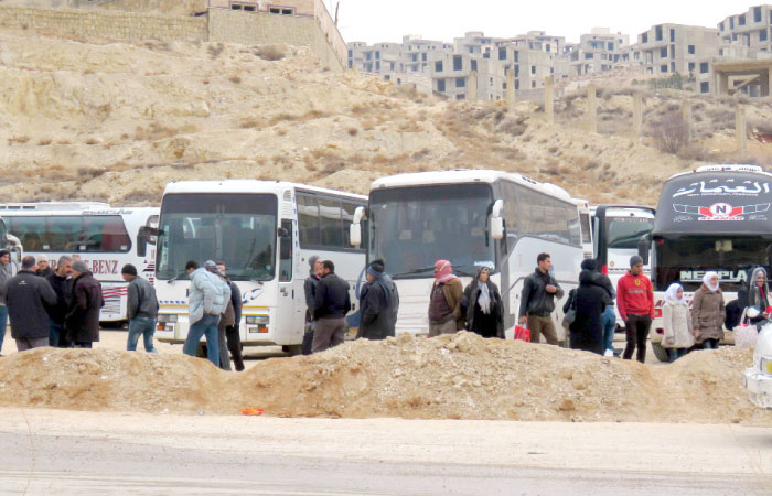 Syrians gather around buses as they prepare to leave the town of Ain Al-Fijah, in the Wadi Barada region, on Saturday. — AFP
