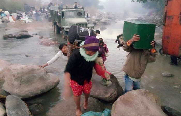Myanmar residents displaced from fighting between ethnic rebel groups and military troops arrive by foot and local trucks to cross the river boundary between Myanmar and China at the border village of Lung Byen near China’s Yunnan province on Wednesday. — AFP
