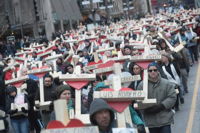 Residents, activists, and friends and family members of victims of gun violence march down Michigan Avenue carrying nearly 800 wooden crosses bearing the names of people murdered in the city in 2016, — AFP