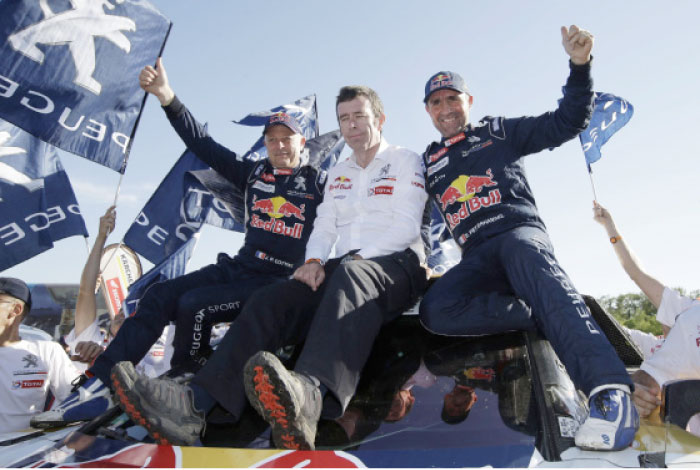 Peugeot driver France’s Stephane Peterhansel (R), co-driver Jean Paul Cottret (L) with team director Bruno Famin (C) cheers after winning the car category at the Dakar Rally upon arrival to the last stage between Rio Cuarto and Buenos Aires, Argentina, Saturday. - AP