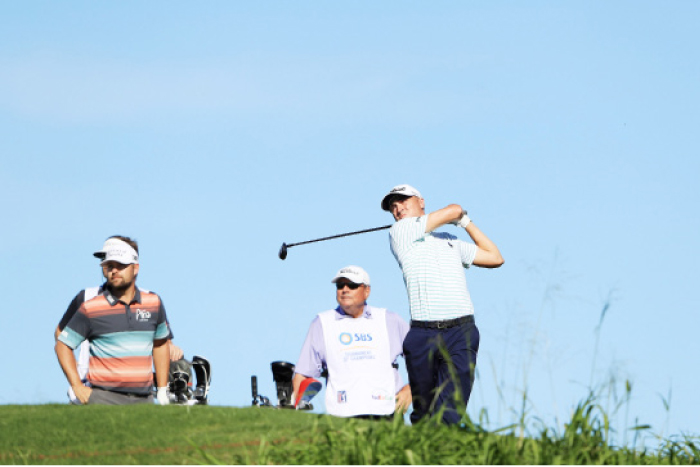 Justin Thomas of the United States plays his shot from the 12th tee as Ryan Moore of the United States looks on during the second round of the SBS Tournament of Champions at the Plantation Course at Kapalua Golf Club in Lahaina, Hawaii, Friday. — AFP