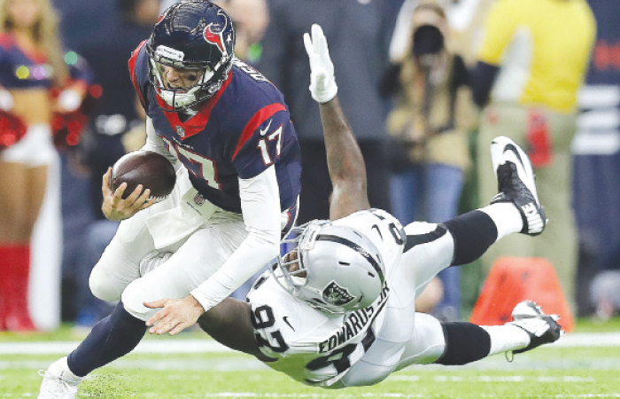 Houston Texans’ quarterback Brock Osweiler (L) scrambles for a first down against Oakland Raiders defensive end Mario Edwards during their AFC wild card NFL game in Houston Saturday. — AP
